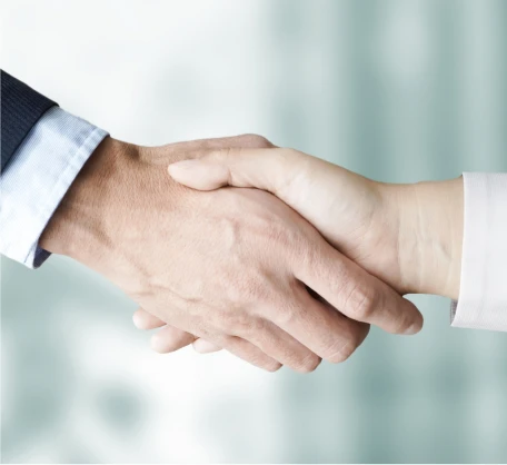 ぼやけた背景を背景に握手する二人の人物。合意またはパートナーシップを象徴しています。.