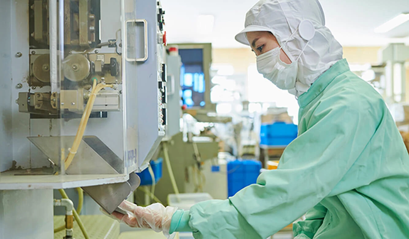 防護服を着た人がクリーンルーム環境で機械を操作します。.