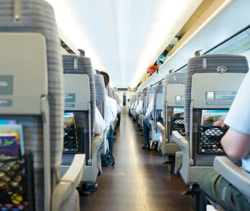 現代の列車の内部。乗客は列になって座り、前方の明るい光に向かっています。.